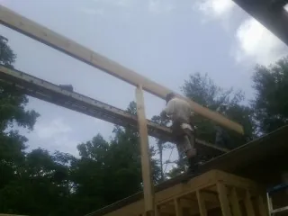 Carpenter setting a ridge beam over a new addition frame — Ice Dam Removal by Roofing Brothers in Saint Bonifacius