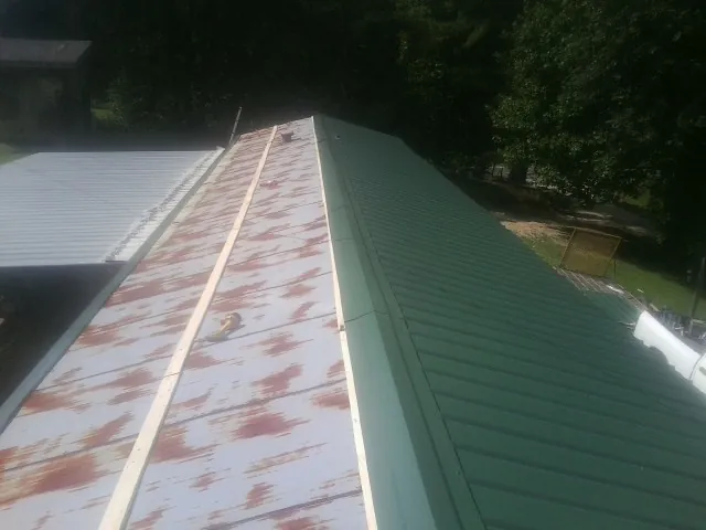 Old rusted panels beside newly installed green metal roofing — Wind Damage Roof Repair by Roofing Brothers in Saint Bonifacius