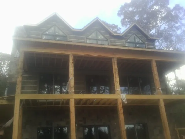 Dormers and porch framing on a large log home under construction — Roof Coating work by our crew in Saint Bonifacius