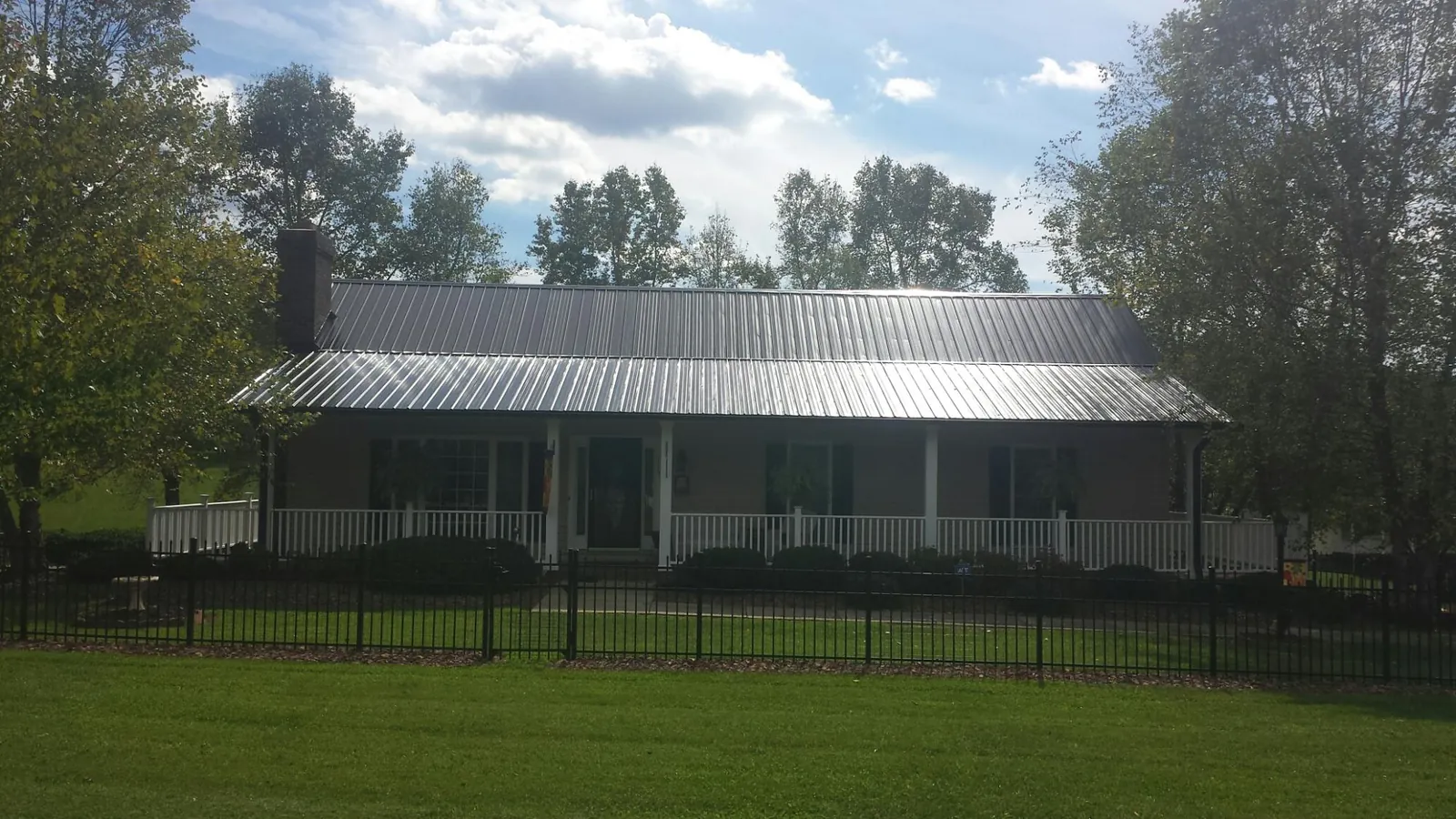 Gray metal roof on a brick ranch with a full width front porch — Gutter Guard Installation work by our crew in Saint Bonifacius